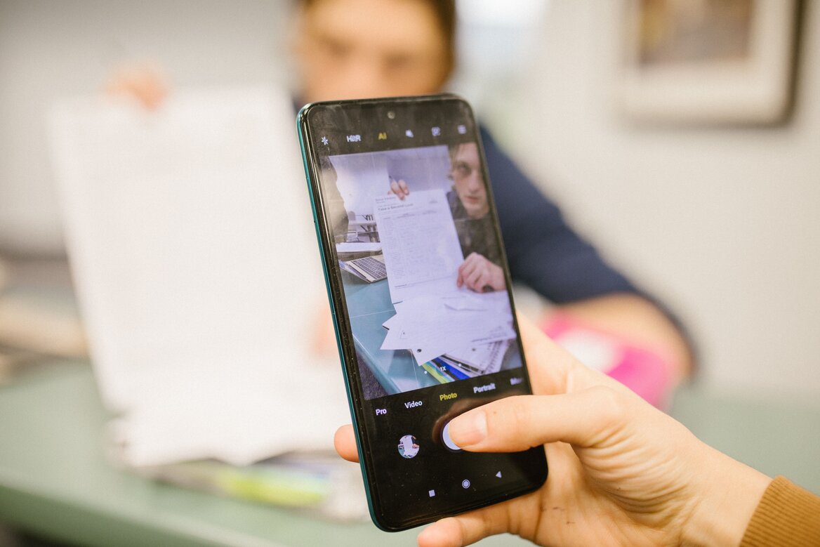 A person using a smartphone to photograph paper documents for expense tracking