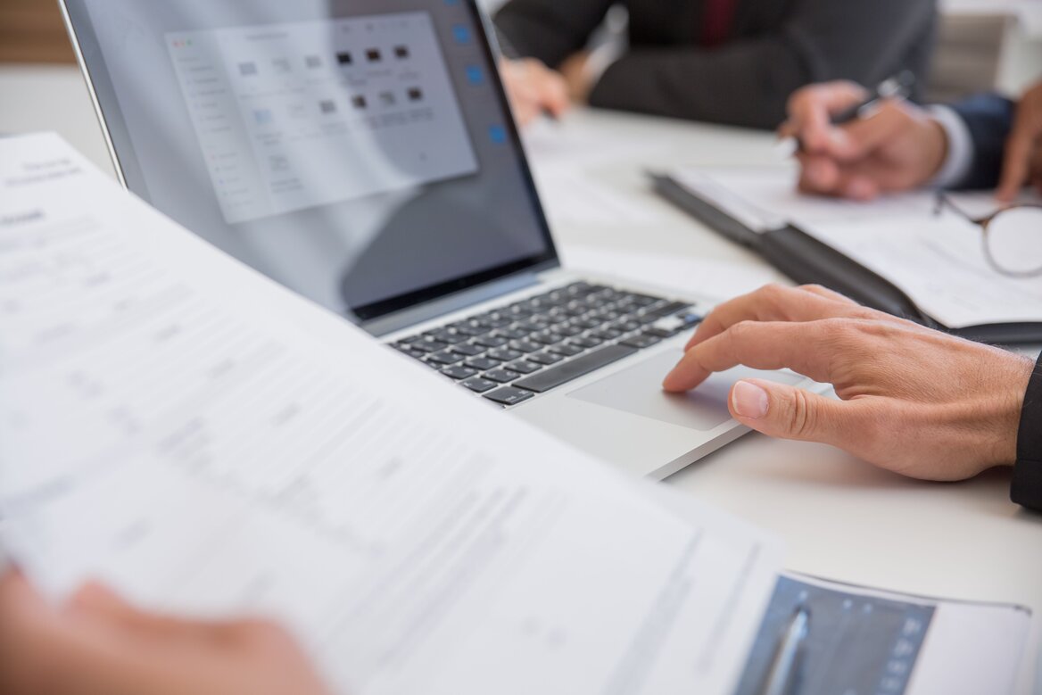 professionals reviewing financial documents on a laptop during an accounting meeting