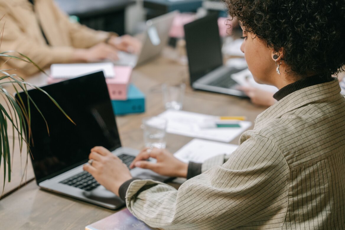 A professional woman using a laptop in a co-working space reading about the guide how to file an quarterly updates