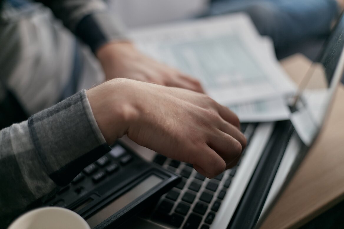 Person reviewing receipts and tax records on a laptop while preparing a Self Assessment tax return.