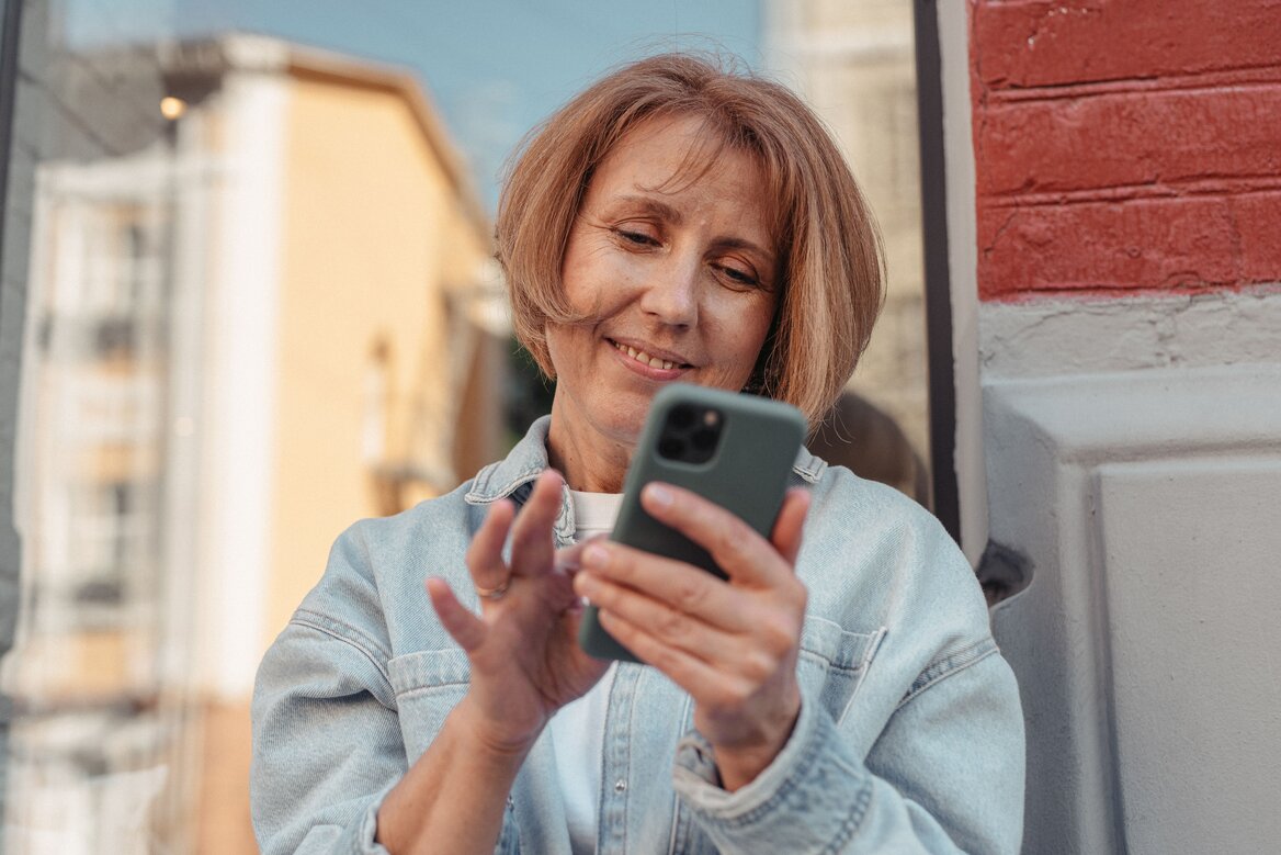 Woman smiling while checking her tax details on a smartphone app