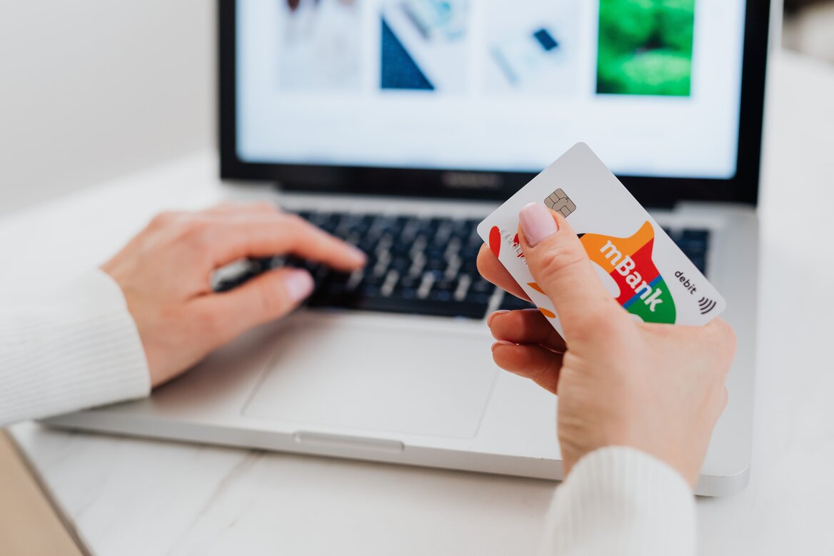 Self-employed woman checking her bank card and phone while working from home