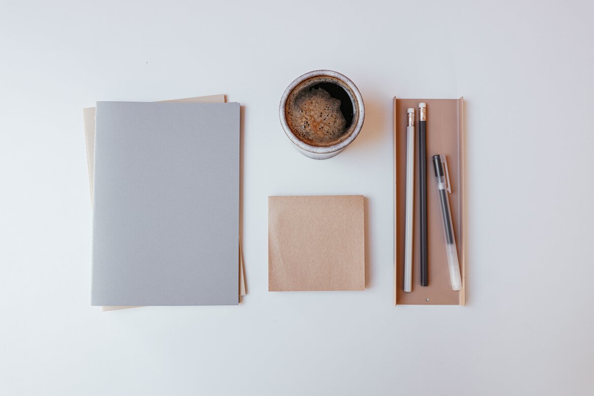 Notebooks, sticky note and pens laid out on a desk representing organised record keeping for small business tax