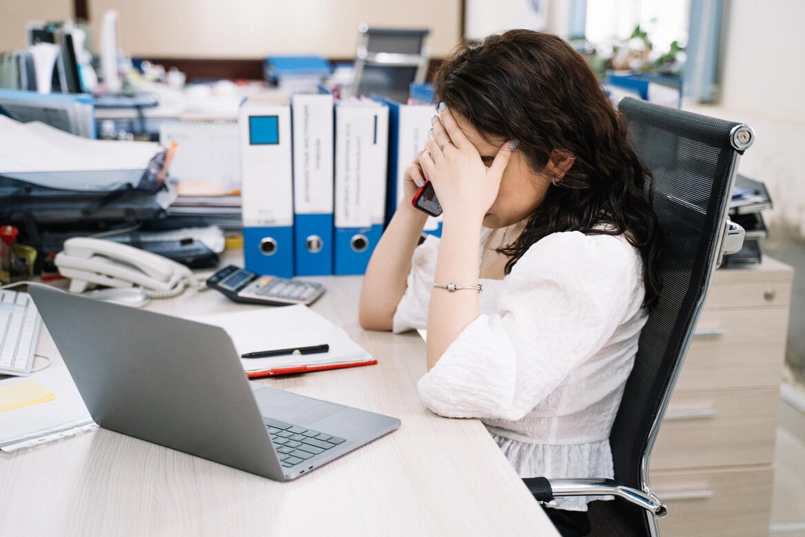 Desk with folders, calculators, a laptop and a phone used for tracking self-employed expense records