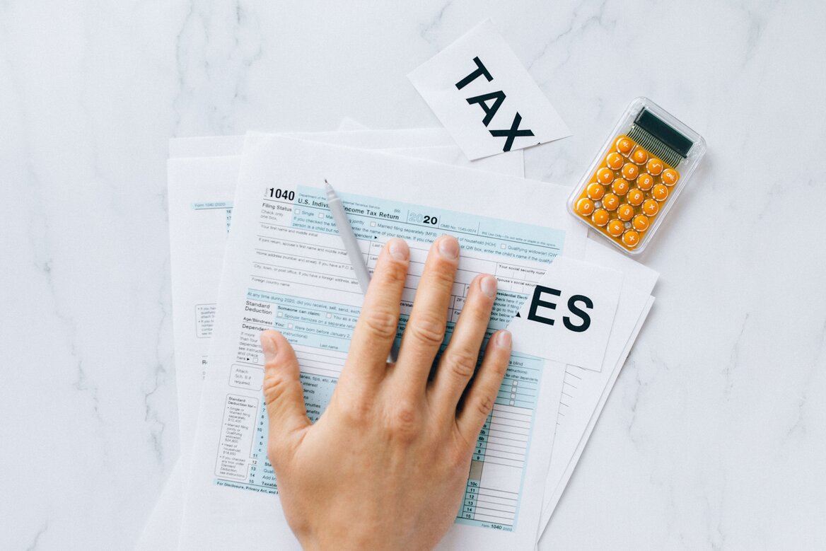 Person filling in a tax return form with a calculator nearby, representing the Self Assessment filing process