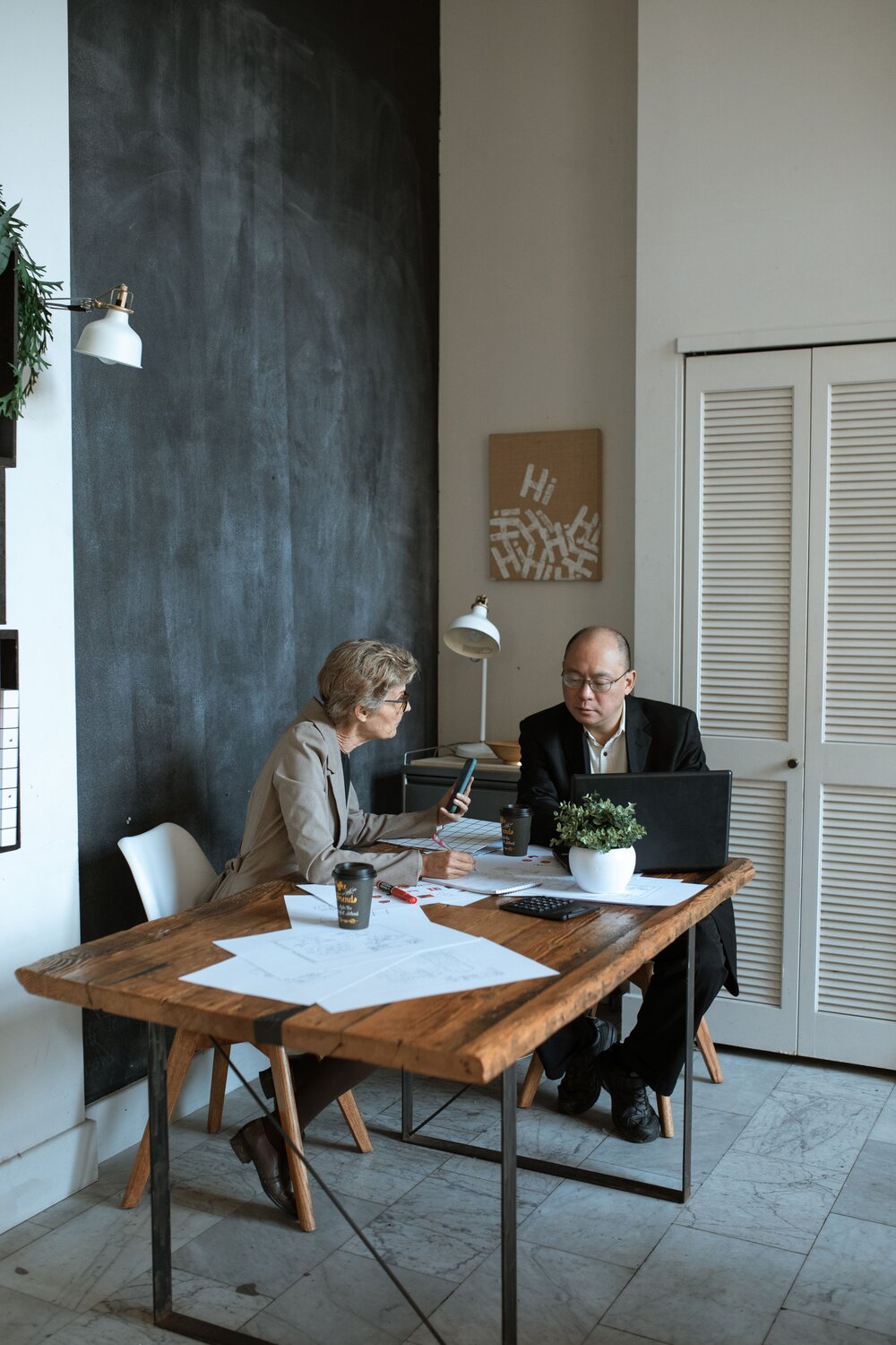 Accountant and Business owner talking while holding a phone and using a laptop
