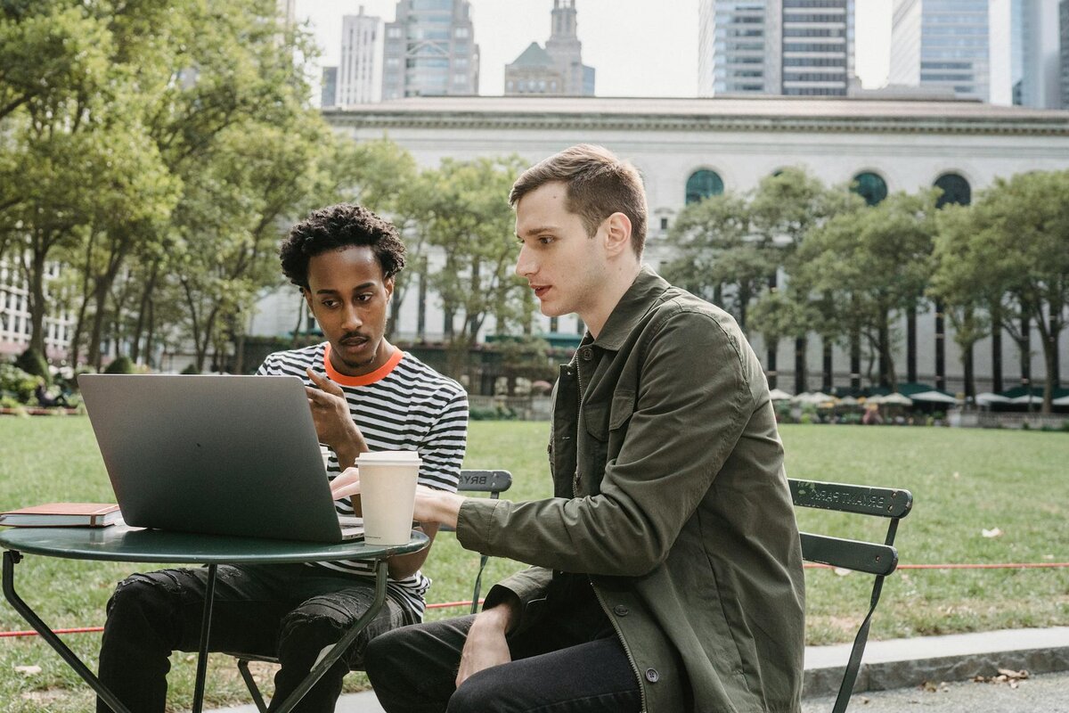 two man at the park on a computer 