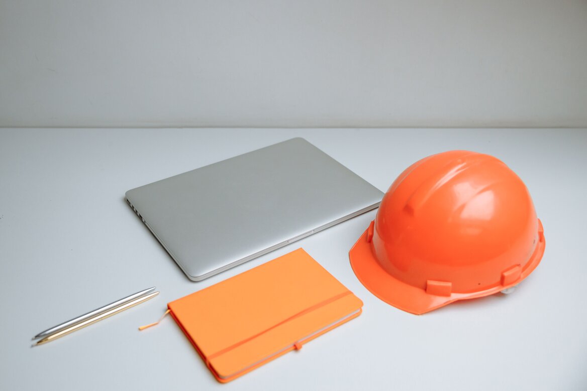 Sleek desk setup featuring a laptop, notebook, and orange hardhat for construction industry making tax digital compliance