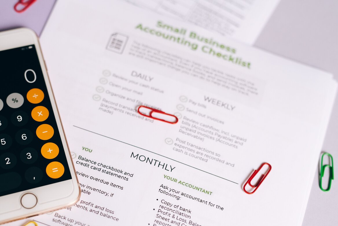 Phone calculator next to a small business accounting checklist with paperclips marking key items