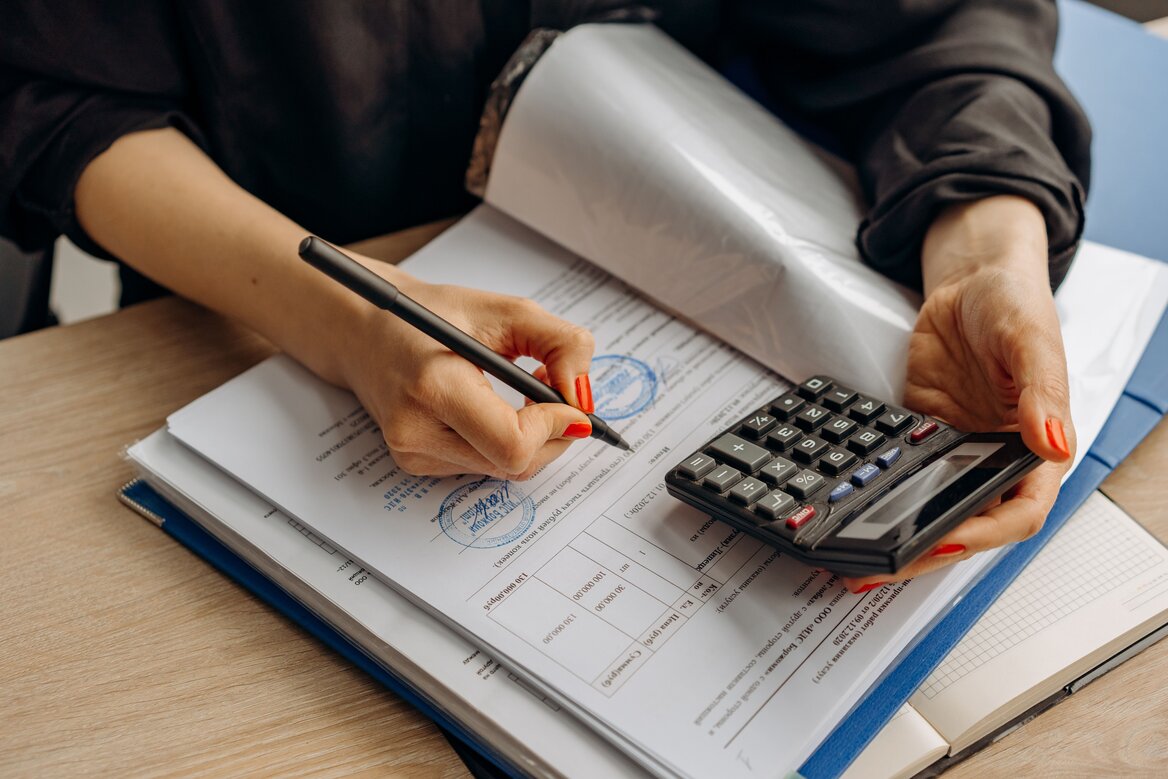 Self-employed person checking a business invoice with a calculator as part of bookkeeping records