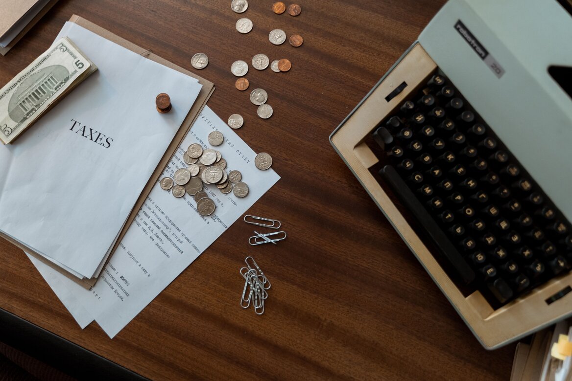 Tax documents and coins on a desk representing HMRC tax calculation season