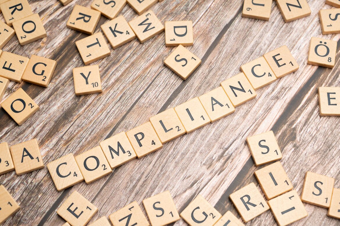 Scrabble tiles spelling the word compliance on a wooden surface representing HMRC tax compliance requirements
