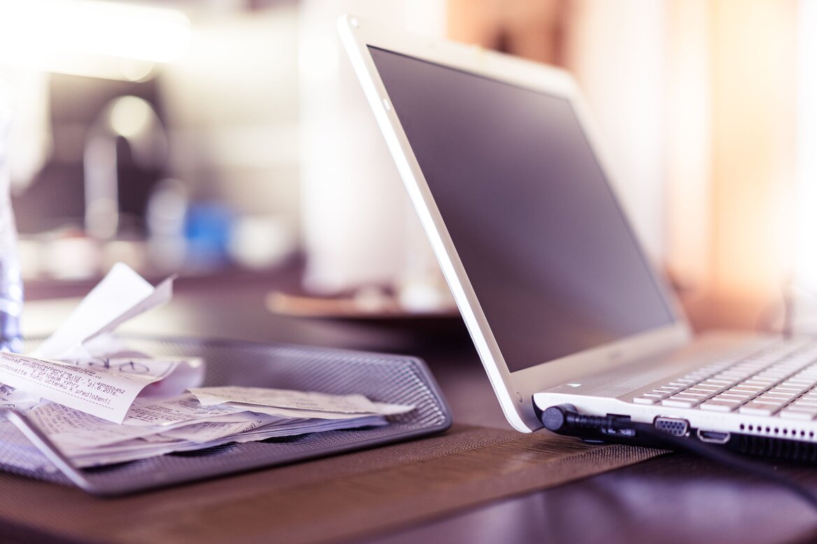 A laptop next to a pile of crumpled receipts, illustrating the expense tracking challenges landlords face before their Self Assessment deadline