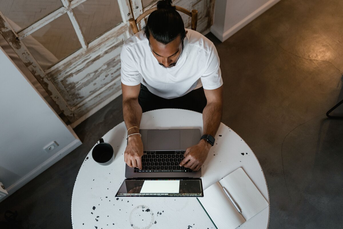Self-employed man working at the table while reviewing documents related to Making Tax Digital requirements for self-employed taxpayers
