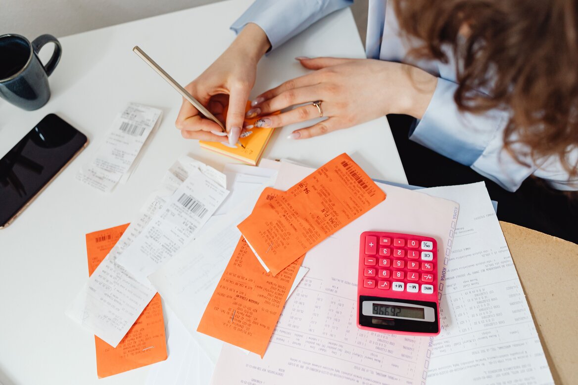 Sole trader organising receipts and using a calculator to prepare records for Self Assessment filing