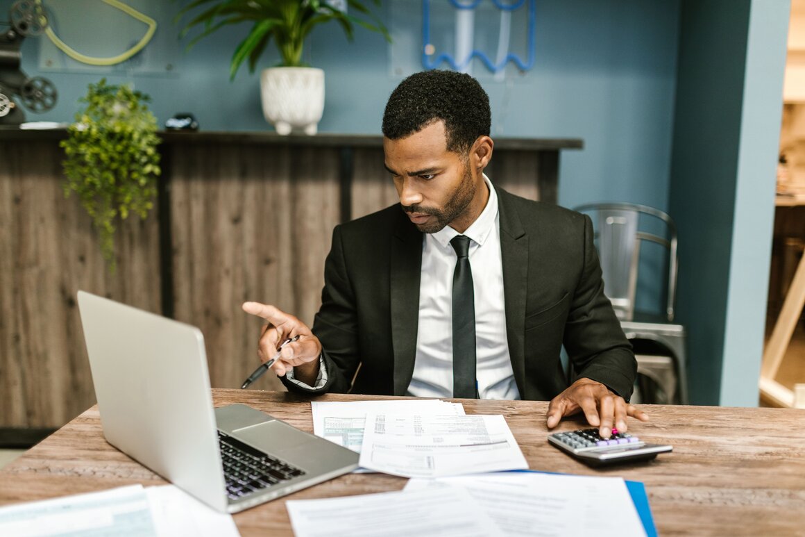 Self-employed man calculating with calculator and notebook