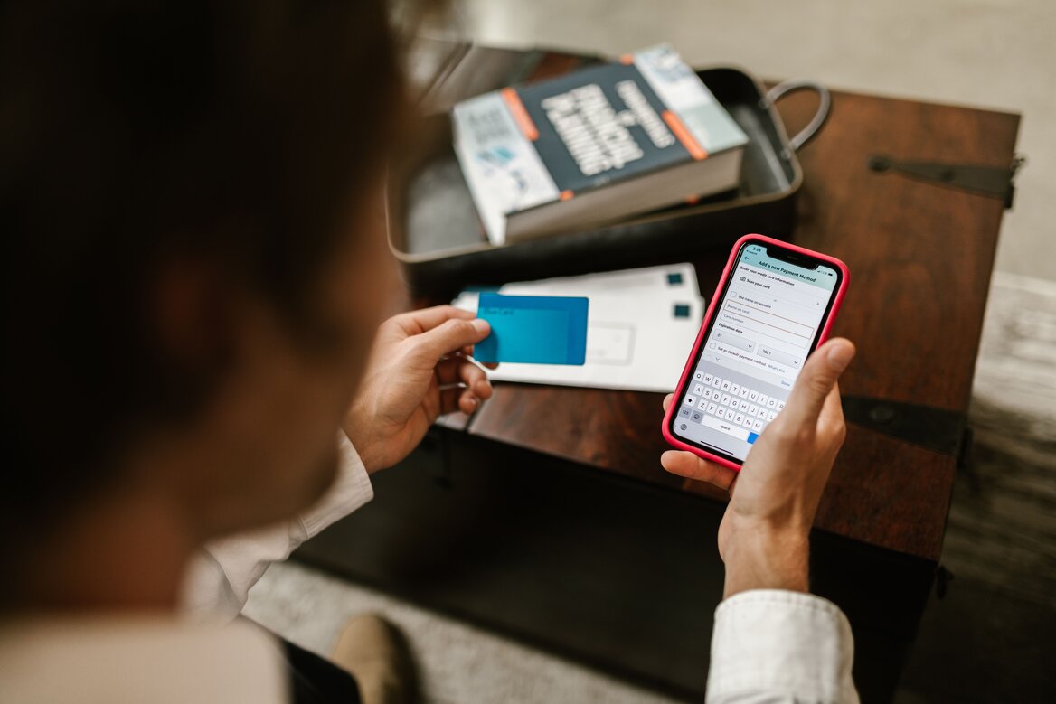 A person managing finances using a mobile app and bank card
