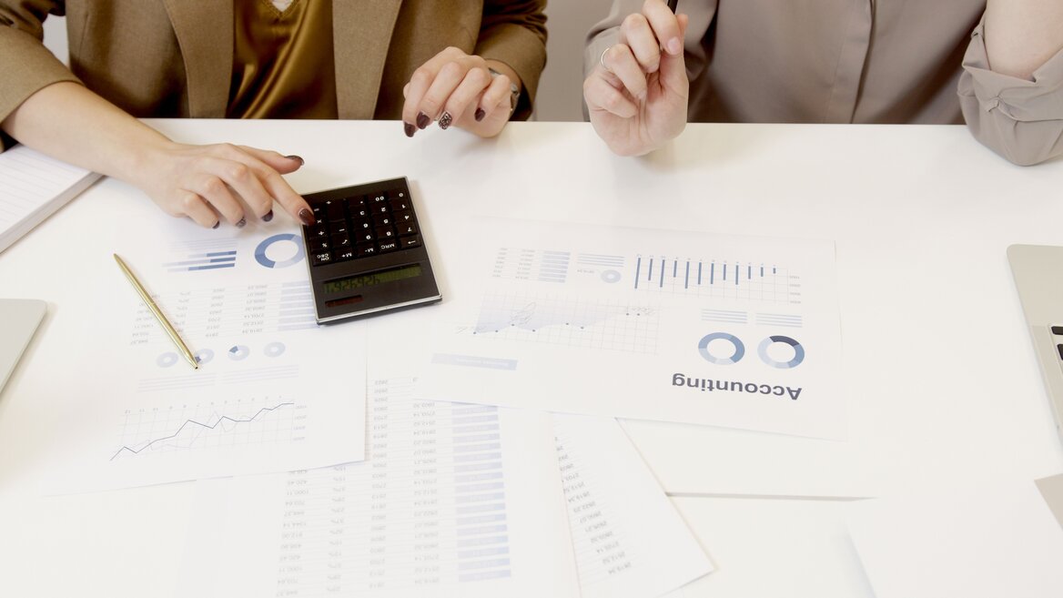 Two people reviewing financial charts and using a calculator to work out a self assessment payment on account