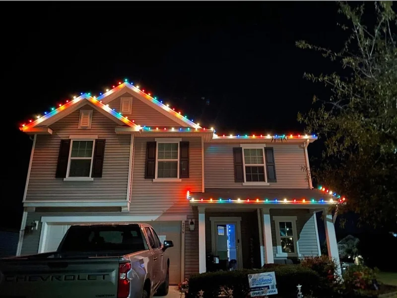 Suburban home decorated with multicolor roofline lighting at night