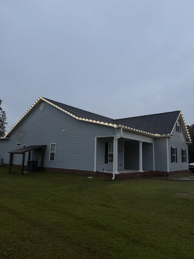 Brick home illuminated with warm holiday lights and a wreath at night