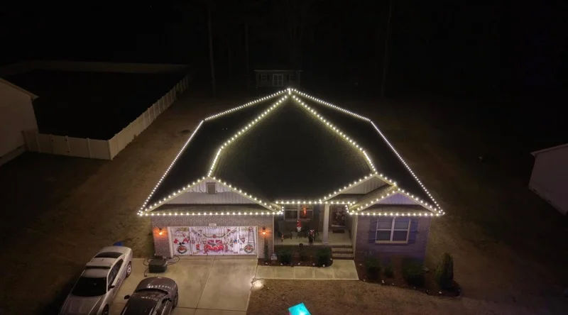 Aerial view of a house outlined with warm white holiday lights