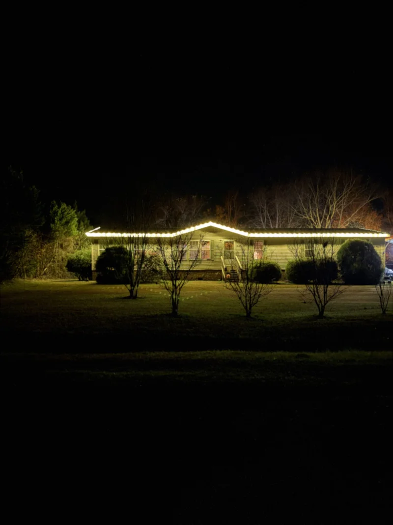 A home illuminated with Christmas lights along the roofline at night