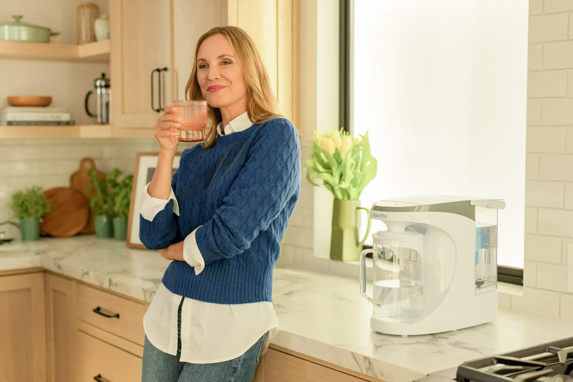 a women in house holding glass of water , and water purifers is place nearby