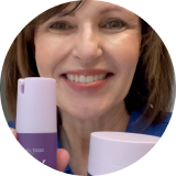 Smiling woman holding two skincare products.