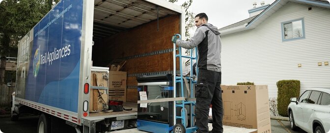 A Trail Appliances delivery work lifting appliances from a truck
