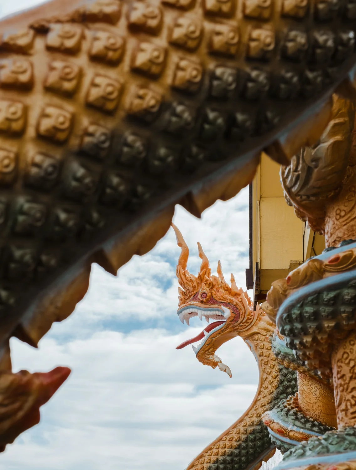 Two serpent-like beings stand across from the lotus pagoda.  These nāga guardians, central to Buddhist lore, are said to have protected the Buddha after his enlightenment, while he meditated during a severe storm. Photo: Peter Vo, Rocky Mountain PBS