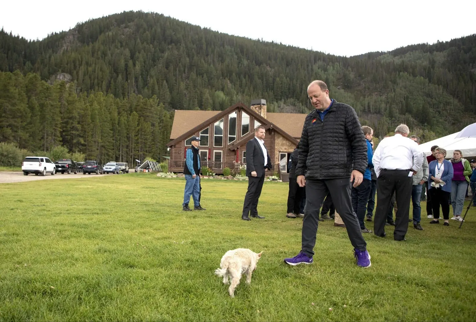 Colorado Gov. Jared Polis walks to pick up his dog, Gia, during a visit at Camp Hale on Tuesday, Aug. 16, 2022, near Leadville.  Photo: Hugh Carey, The Colorado Sun
