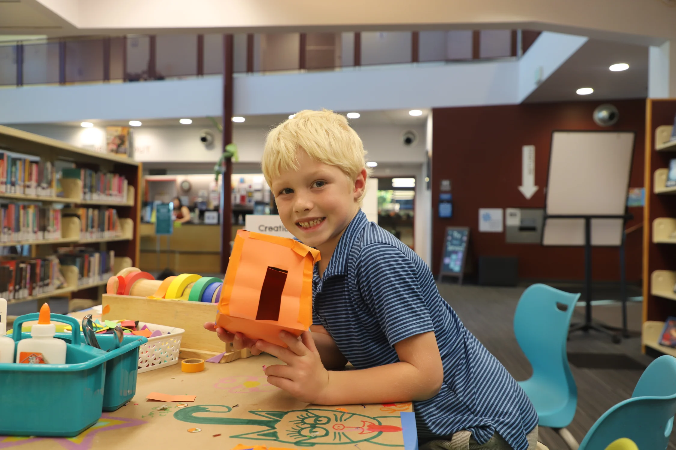 Jackson, 8, makes crafts at the Ross-University Hills Library Branch. Photo: Alec Berg, Rocky Mountain PBS