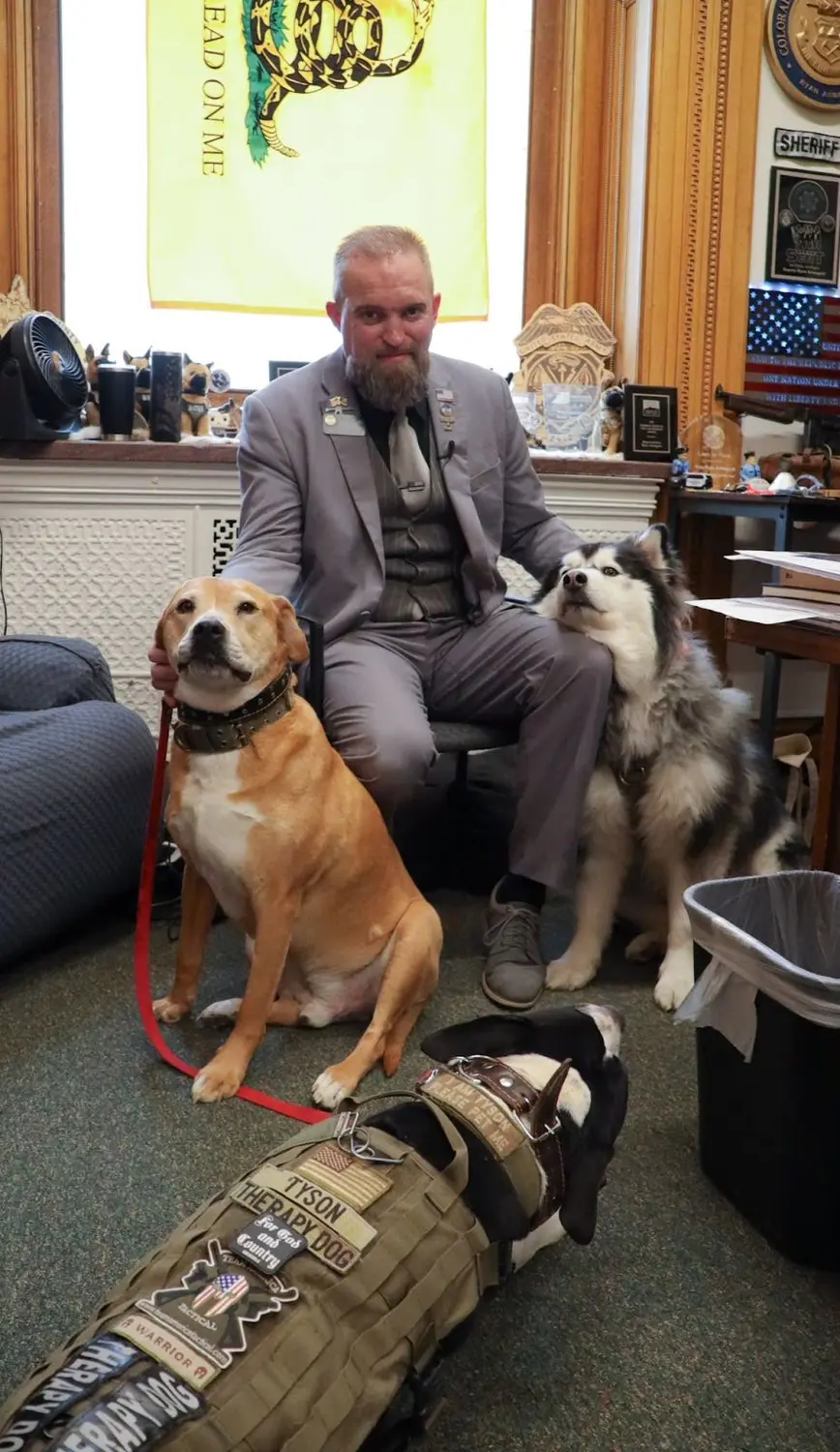 State Rep. Ryan Armagost, R-Berthoud, and three of his four dogs in Armagost’s Colorado Capitol office.  Photo: Carly Rose, Rocky Mountain PBS