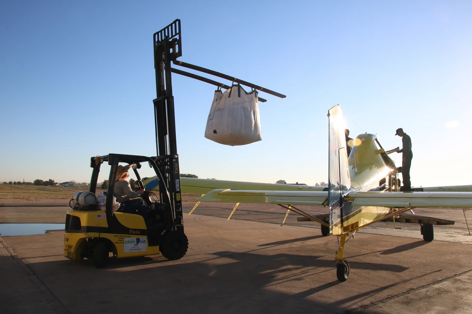 Joseph Daviss uses a forklift to load a mix of sorghum, rye, radish and turnip seeds into an Air Tractor plane. Pilot, Neil Wicke, spread the seeds over a corn field in Ault. Photo: Emma VandenEinde, KUNC. 