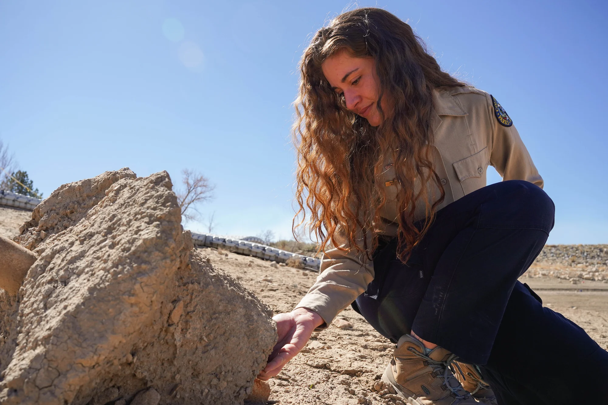 Baker looks for mussels under a piece of concrete that was once submerged in the lake. Small narrow areas are the preferred home of the invasive species. Photo: Joshua Vorse, Rocky Mountain PBS