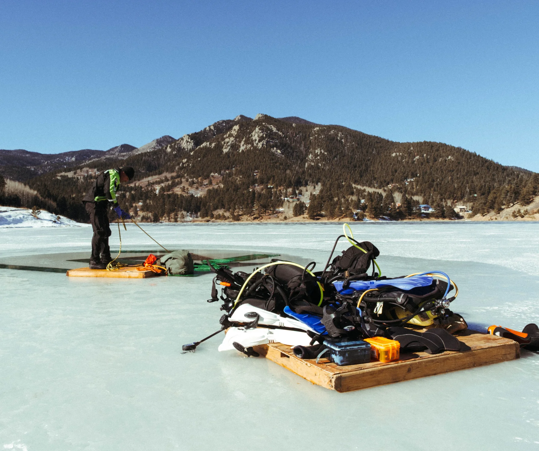 Divers bring wooden pallets onto the lake so their gear doesn't stick to the ice as the sun comes out. Photo: Peter Vo, Rocky Mountain PBS