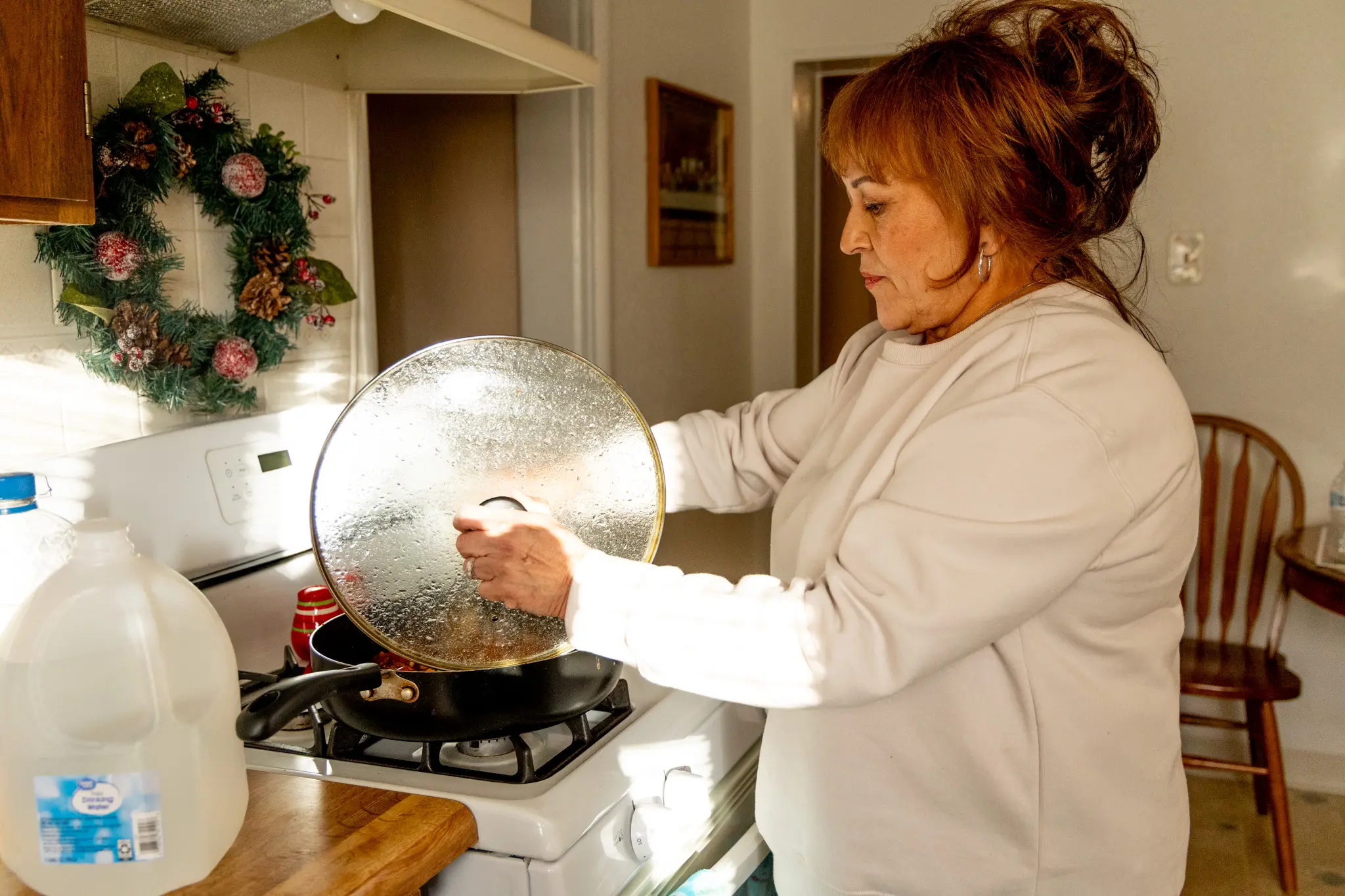 Carla Quintana, 64, cooks with a gallon of water for her father. Photo: Priya Shahi, Rocky Mountain PBS