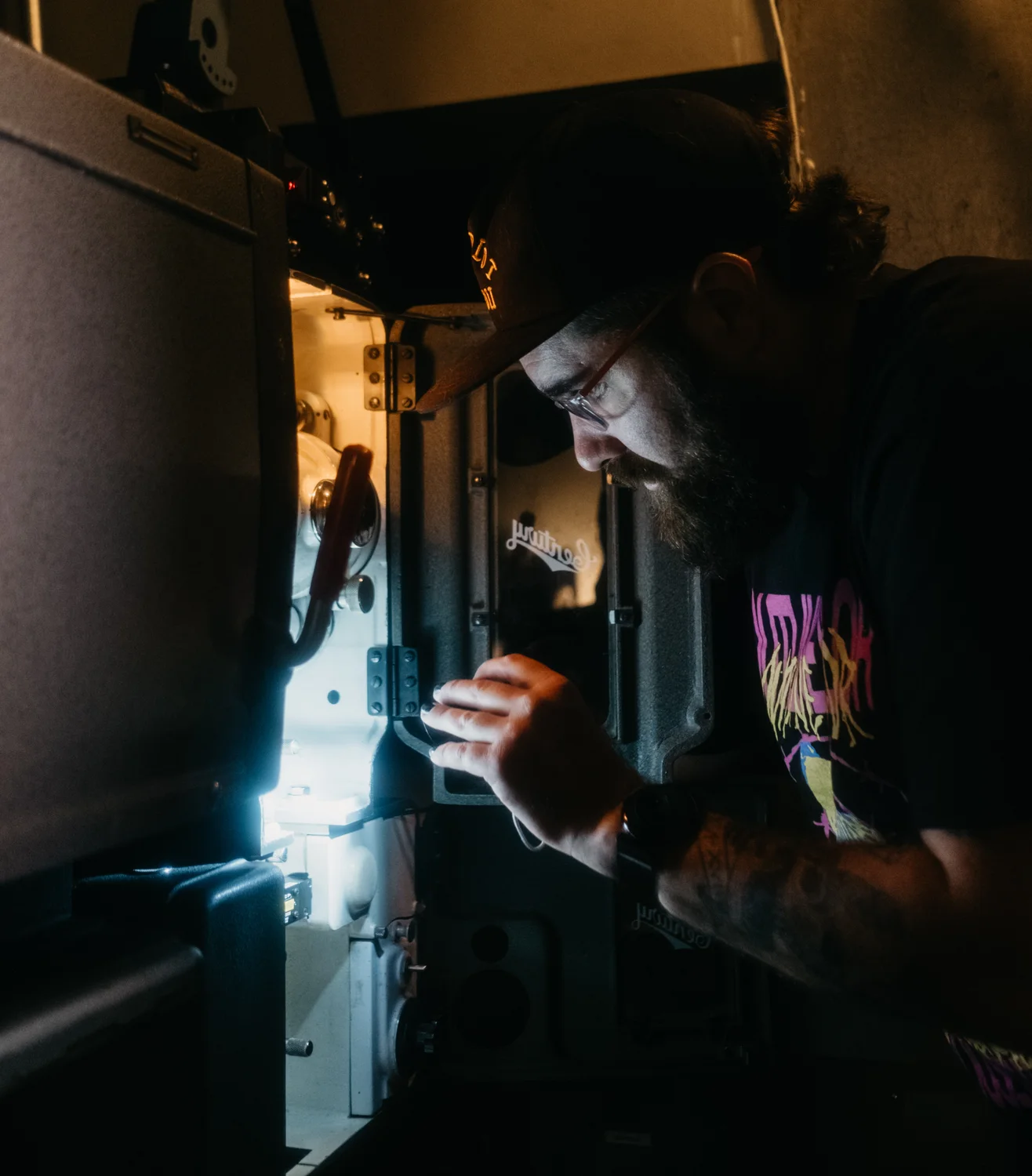 Whitney Miller inspects the reel inside the projector. Photo: Peter Vo, Rocky Mountain PBS