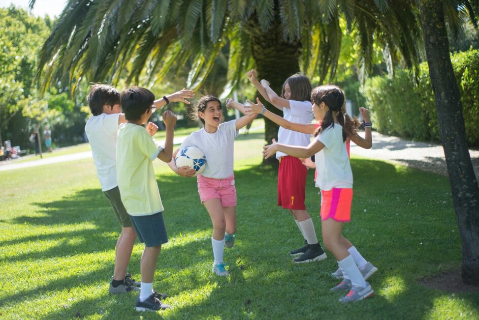 A group of kids hanging out together with a soccer ball.