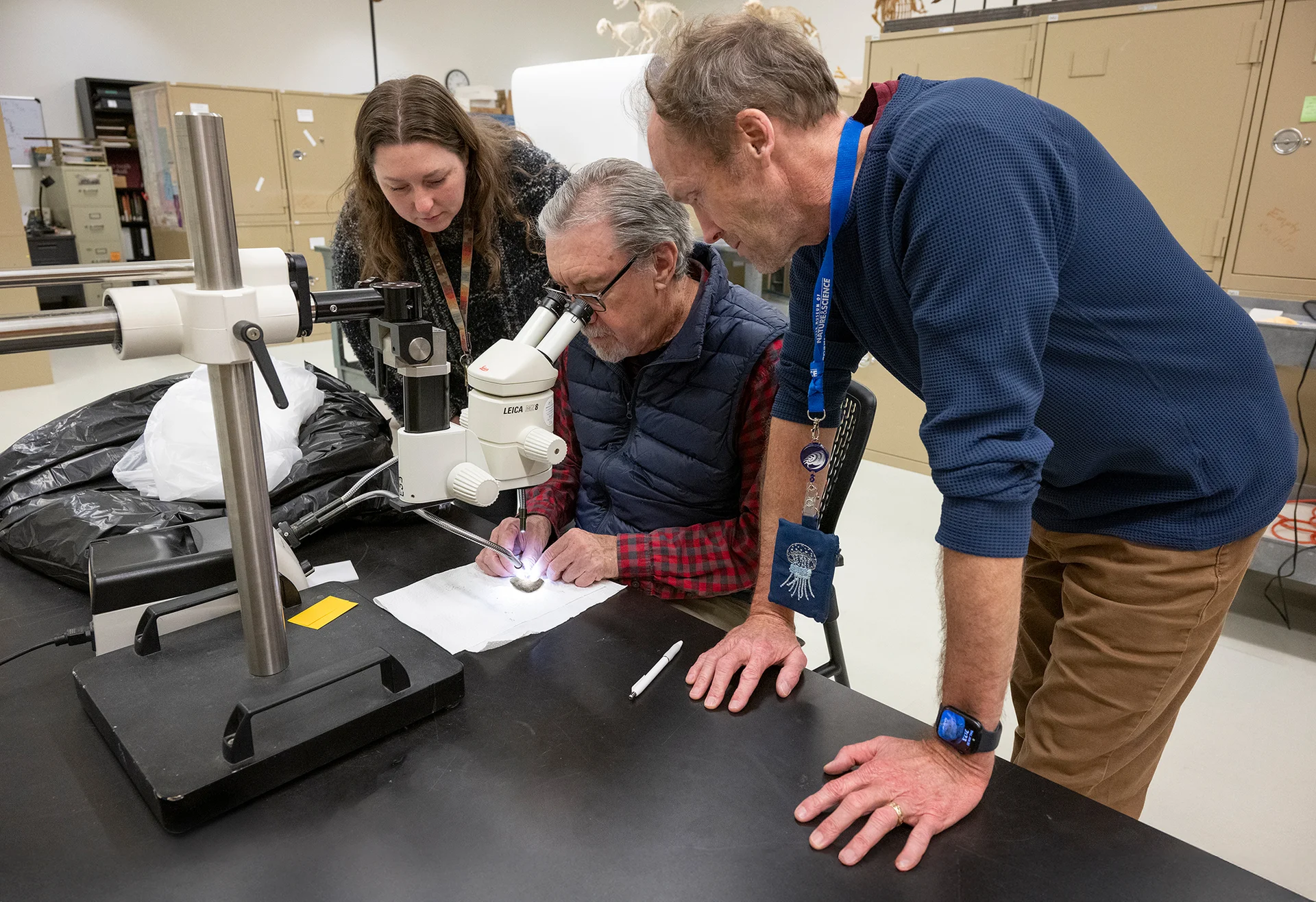 Gussie Maccracken, David Krause and Patrick O'Connor study the dinosaur fossil. Photo courtesy Rick Wicker, DMNS
