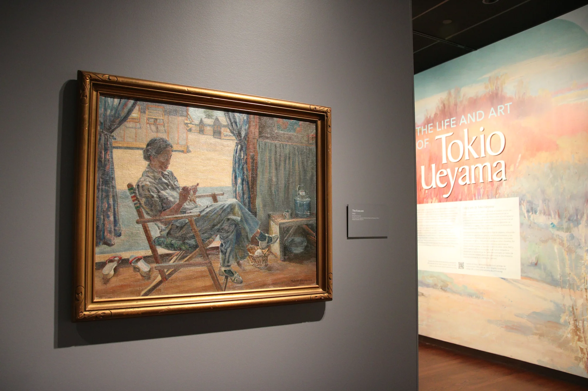 Tokio Ueyama's The Evacuee hangs in the Denver Art Museum as part of "The Life and Art of Tokio Ueyama" exhibit on July 29, 2024. The oil painting on canvas shows the Santa Anita Assembly Center in the background, where thousands of Japanese-Americans stayed before being transferred to incarceration camps. Photo: Emma VandenEinde, KUNC