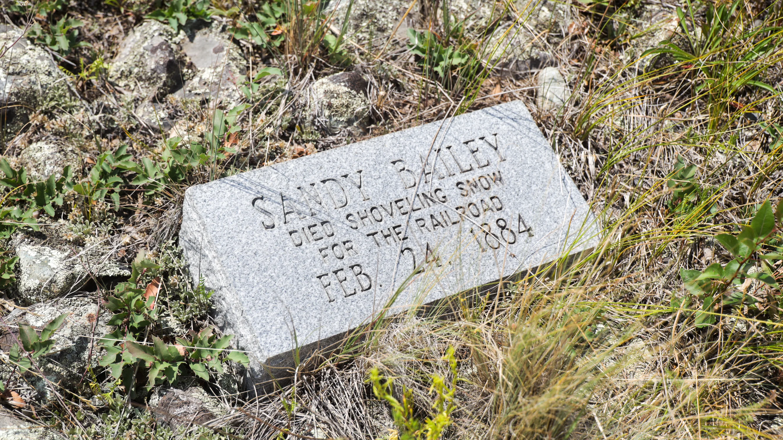 A gravestone reads, “Sandy Bailey. Died shoveling snow for the railroad.” Photo: Ziyi Xu, Rocky Mountain PBS