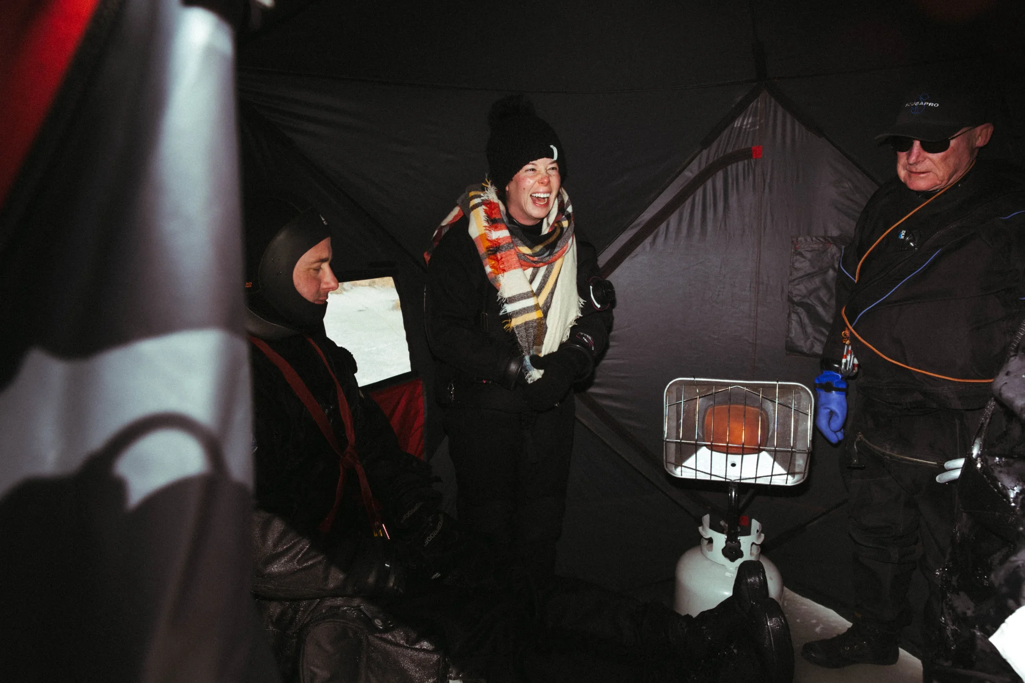 Brooke Near, Kevin Simpson and Ed Miller warm up in the red Eskimo tent after their dives. Photo: Peter Vo, Rocky Mountain PBS