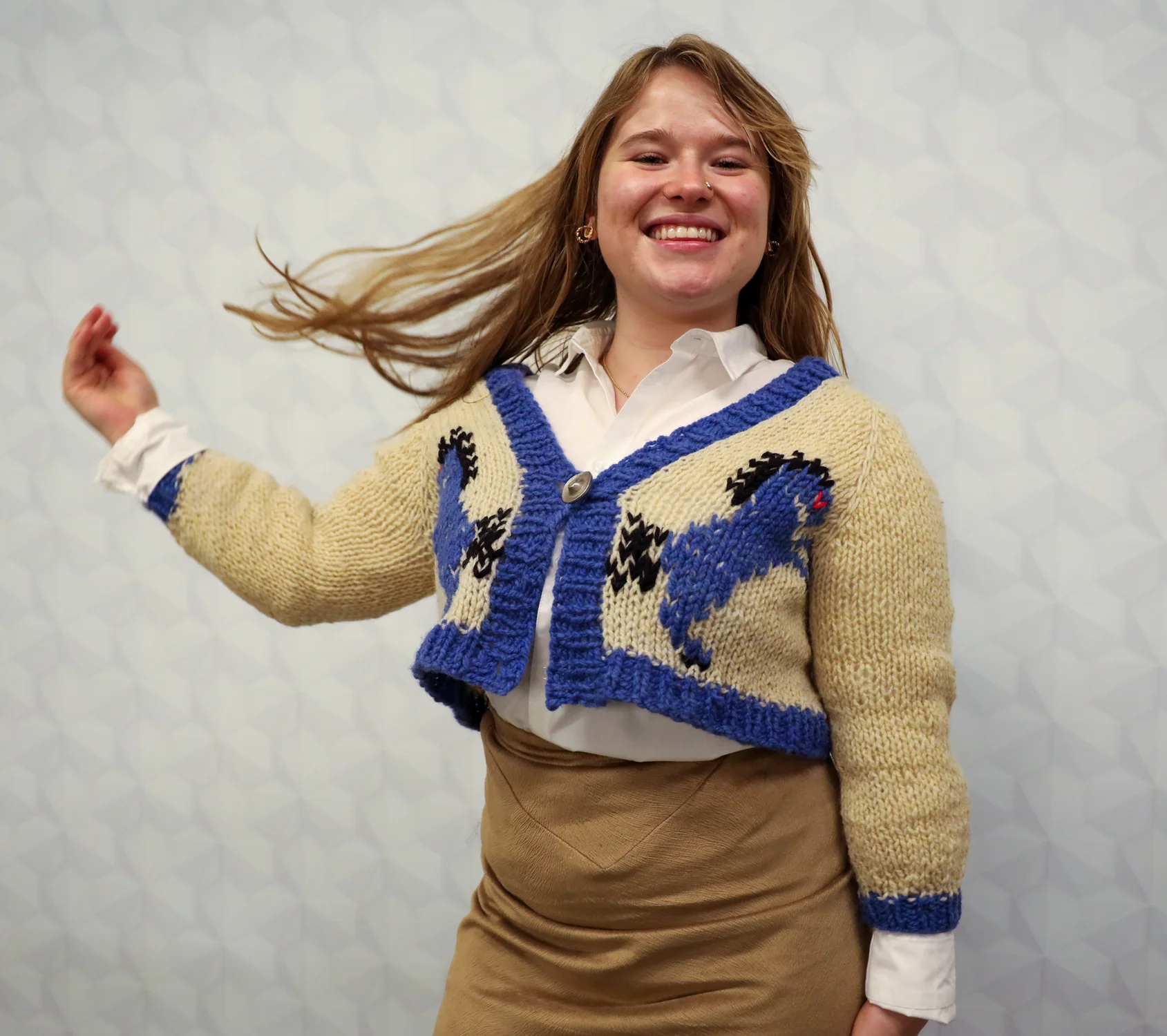 CSU apparel design and production senior Ella McBride used the yarn from a thrifted wool sweater to create the cardigan, featuring Denver International Airport’s notorious Blucifer. She made the button down shirt from an old sheet.  “I really like the idea of taking something that would be thrown away and making it into something that somebody would actually wear,” McBride said.  Designed by Ella McBride and modeled by Elise Golyer. Photo: Carly Rose, Rocky Mountain PBS