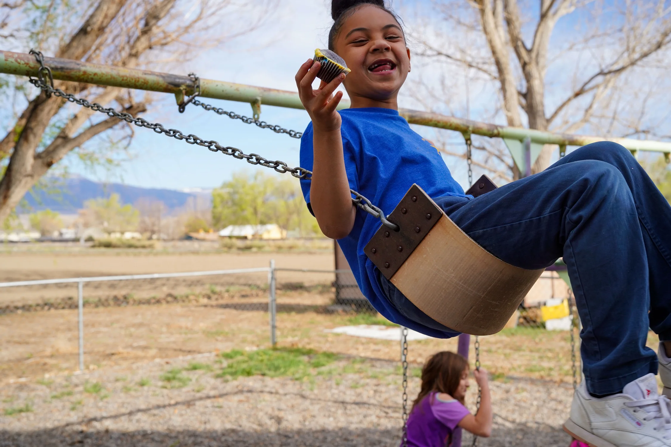 Tai Tautua’a, age six, swings while eating a cupcake at the Hub after school on Monday, April 7. Her blue Clifton Elementary t-shirt will become vintage on May 21, 2025, the last day of school ever for Scenic, Nisley, and Clifton Elementary schools in the Grand Valley. Photo: Joshua Vorse, Rocky Mountain PBS