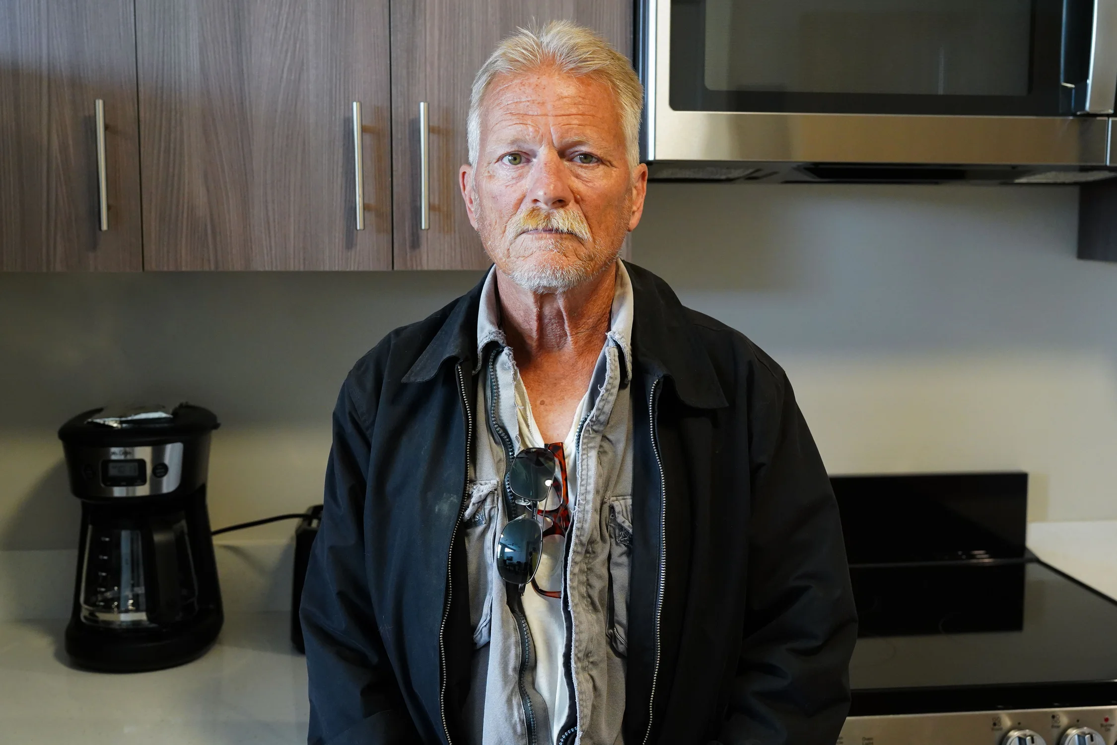 Elmore stands for a photo in his kitchen just after getting the keys to his place. Along with stainless steel appliances, the kitchen is stocked with basic dishes and cleaning supplies. Photo: Joshua Vorse, Rocky Mountain PBS