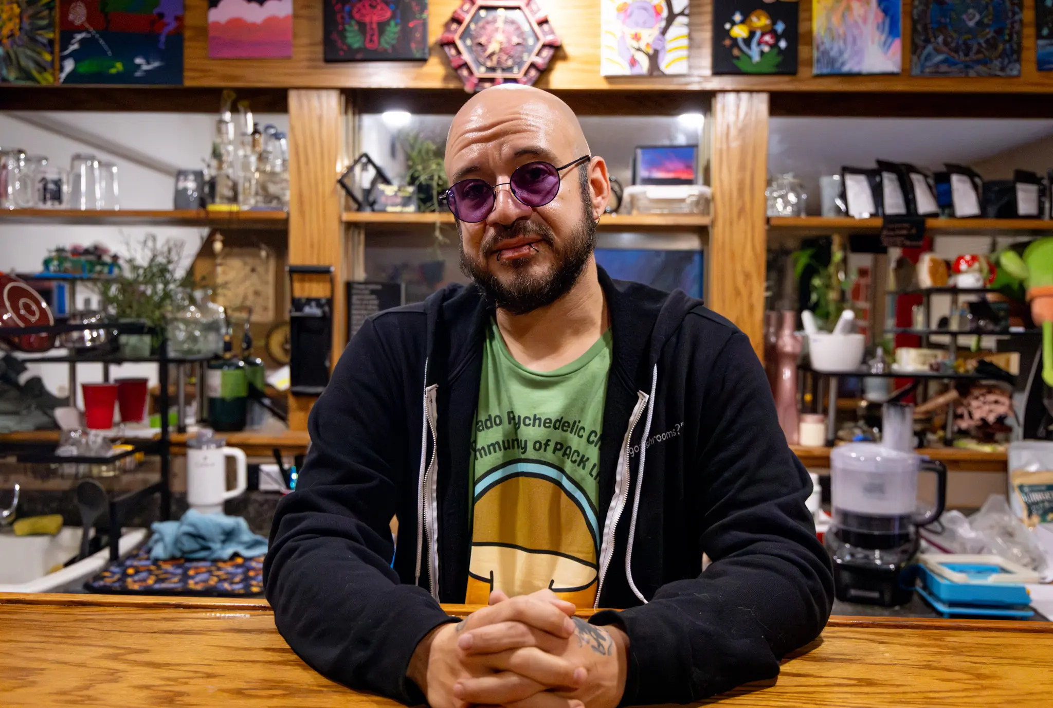 Benji Dezaval, who goes by Teopixqui Dez, founded the Colorado Psychedelic Church. He poses behind the psychedelic bar at his house, which serves as the church. Photo: Priya Shahi, Rocky Mountain PBS