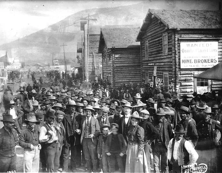 Crowd of men and women waiting for mail at the Dawson post office, Yukon Territory, 1899. Public Domain.