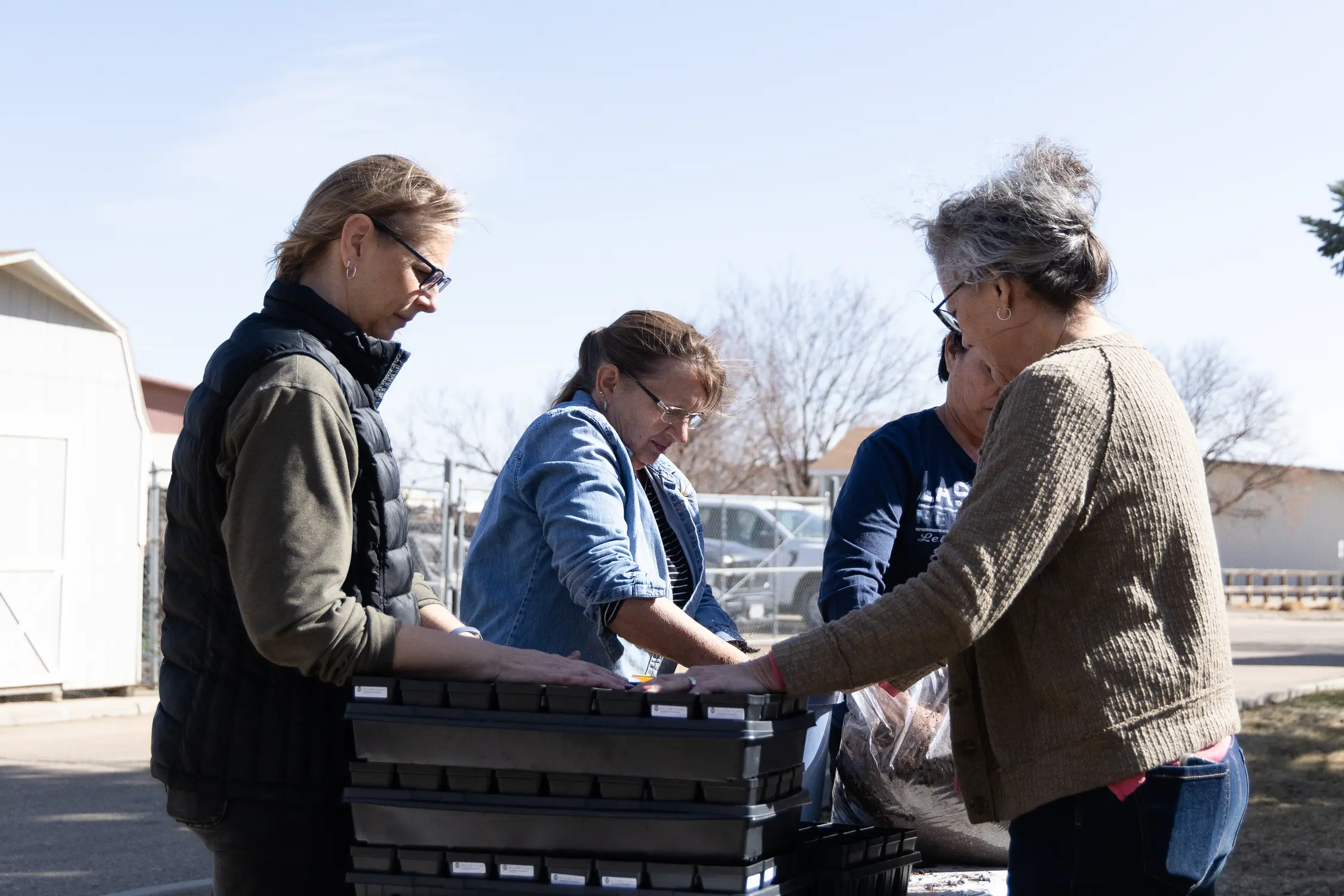 Volunteers with the Colorado State University Extension add soil to plastic seed containers. Photo: Cormac McCrimmon, Rocky Mountain PBS