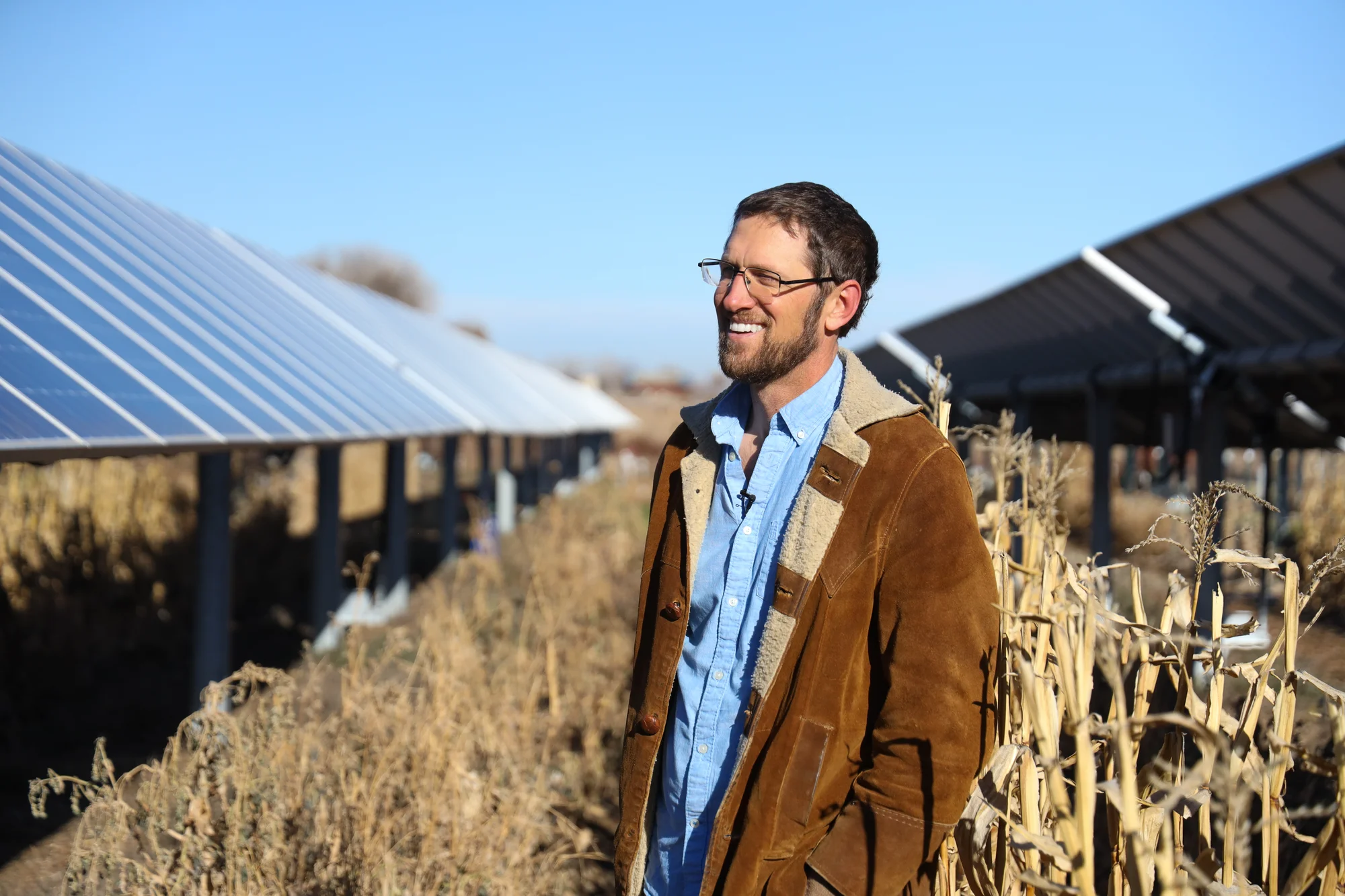 Kominek stands in between a row of solar panels at his farm in Longmont, Colorado. Photo: Cormac McCrimmon, Rocky Mountain PBS